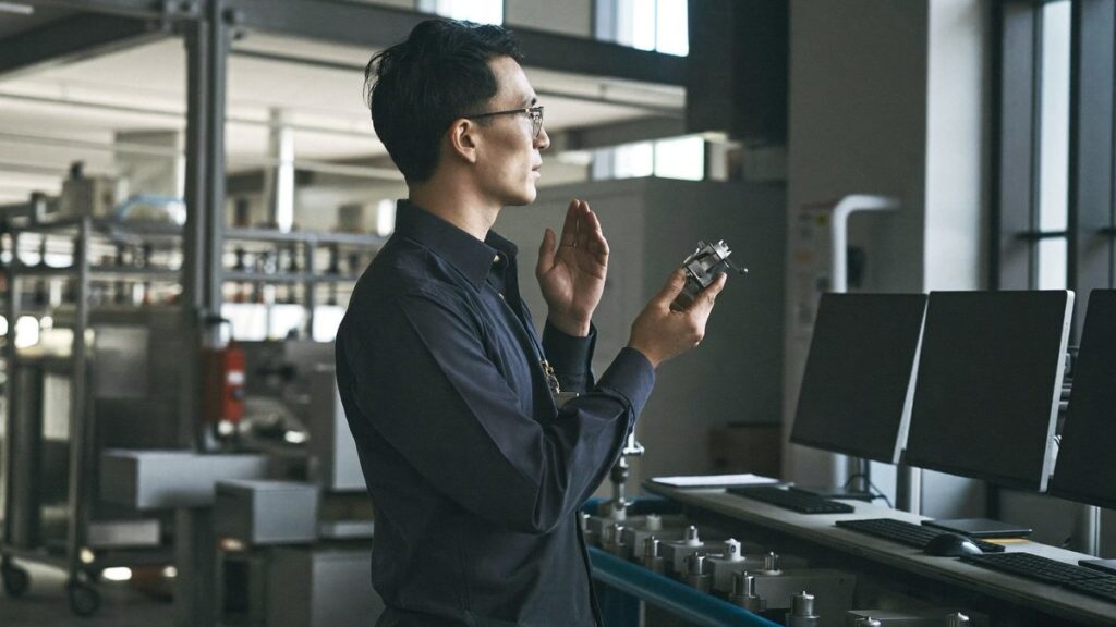 Quality KPIs in manufacturing: a supervisor inspecting a metal part beside the production line